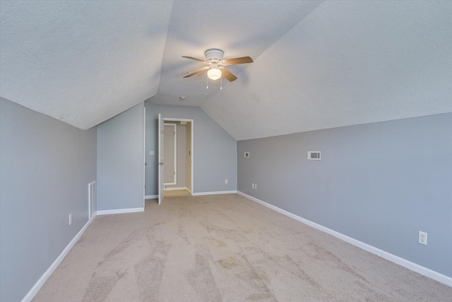 bonus room with vaulted ceiling, ceiling fan, light colored carpet, and a textured ceiling