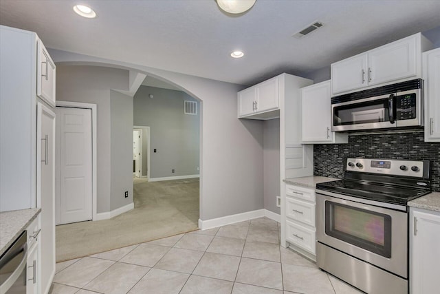 kitchen featuring white cabinets, light colored carpet, light stone countertops, and stainless steel appliances