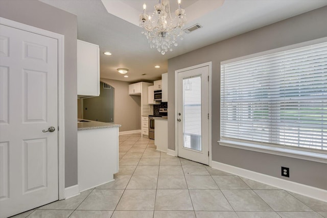 kitchen featuring decorative light fixtures, light tile patterned floors, a notable chandelier, white cabinetry, and stainless steel appliances