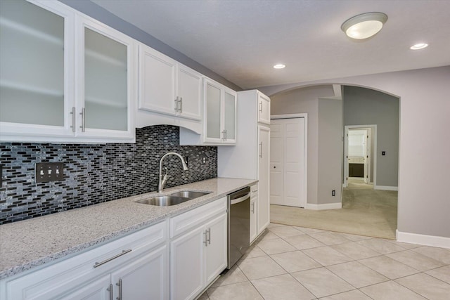 kitchen featuring sink, light stone counters, stainless steel dishwasher, light colored carpet, and white cabinets