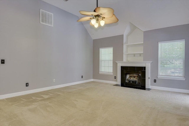 unfurnished living room with a tile fireplace, ceiling fan, carpet floors, and lofted ceiling