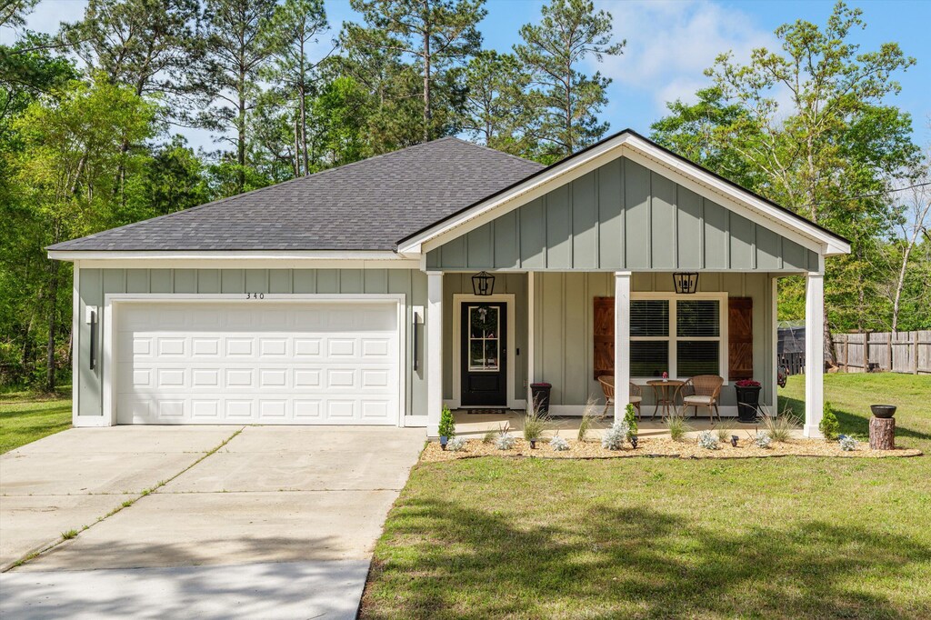 340 Church St, Blythe, GA 30805 - view of front of home with concrete driveway, an attached garage, a front lawn, a shingled roof, and covered porch