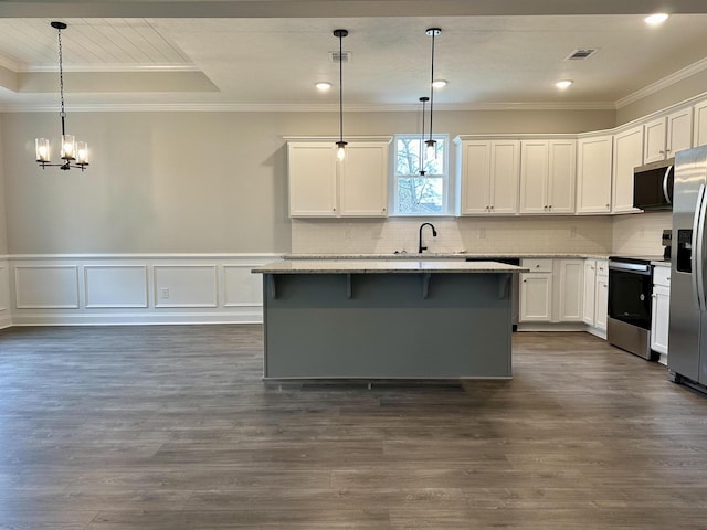 kitchen with a kitchen island, a notable chandelier, pendant lighting, white cabinets, and appliances with stainless steel finishes