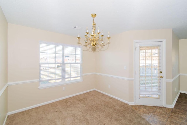 carpeted empty room with an inviting chandelier