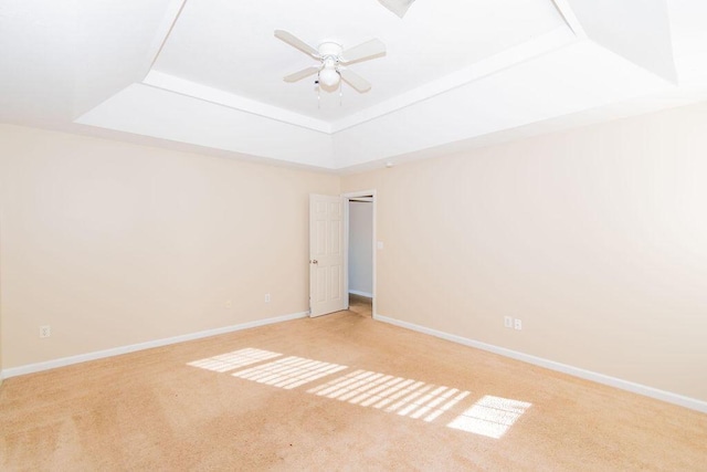 carpeted empty room featuring a raised ceiling and ceiling fan