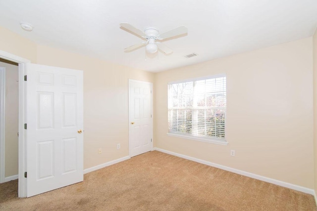 spare room with light colored carpet and ceiling fan