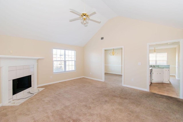 unfurnished living room with ceiling fan with notable chandelier, light colored carpet, sink, and a tile fireplace