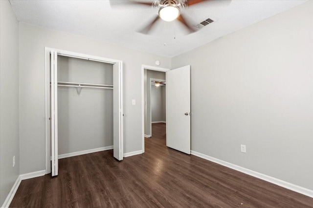 unfurnished bedroom featuring dark wood-type flooring, a closet, visible vents, and baseboards