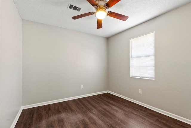 unfurnished room with a textured ceiling, dark wood-type flooring, a ceiling fan, visible vents, and baseboards