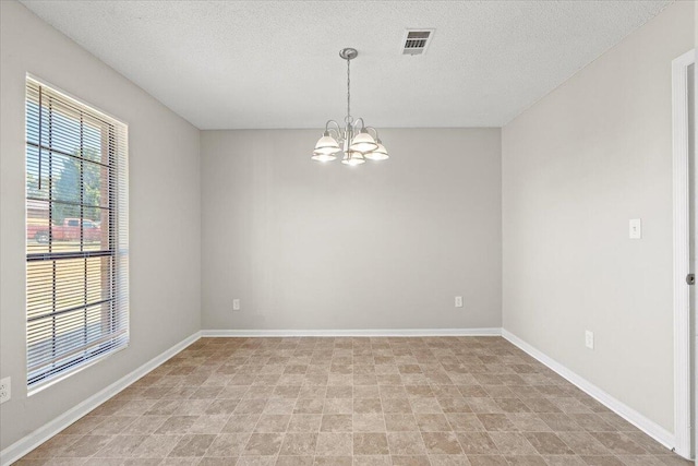 unfurnished room with an inviting chandelier, baseboards, visible vents, and a textured ceiling