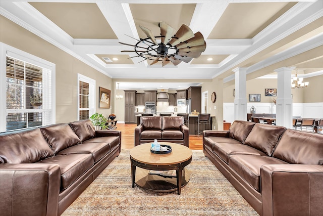 living room featuring ornate columns, ceiling fan with notable chandelier, ornamental molding, coffered ceiling, and light wood-type flooring