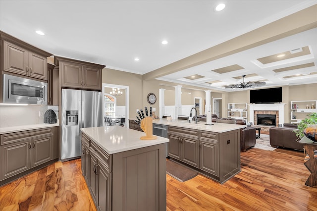 kitchen with coffered ceiling, gray cabinets, a kitchen island, stainless steel appliances, and a fireplace