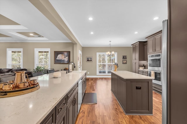 kitchen featuring crown molding, a healthy amount of sunlight, sink, and a kitchen island with sink