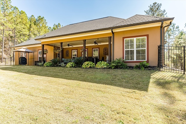 rear view of house featuring a yard and ceiling fan