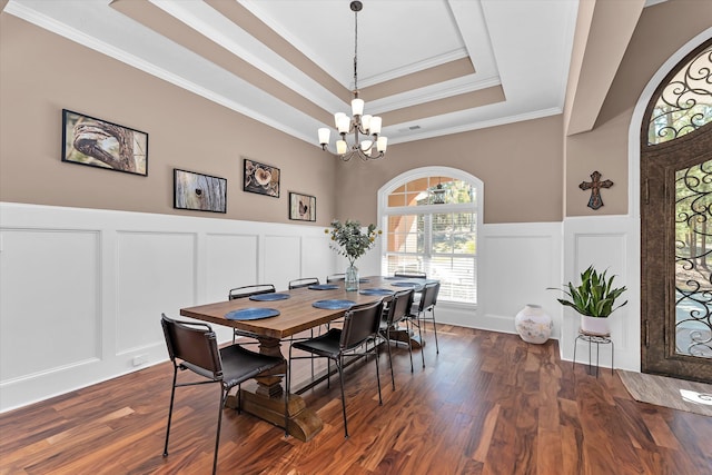 dining area featuring dark hardwood / wood-style flooring, a tray ceiling, ornamental molding, and a chandelier