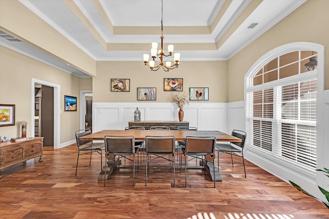 dining area featuring hardwood / wood-style flooring, ornamental molding, a raised ceiling, and a chandelier