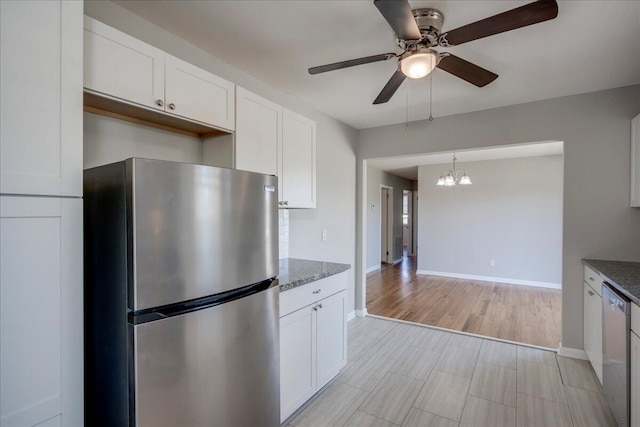 kitchen with ceiling fan with notable chandelier, white cabinets, dark stone counters, and appliances with stainless steel finishes