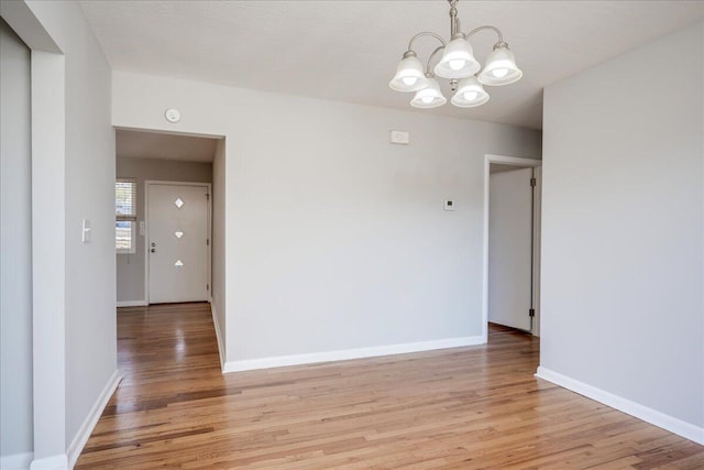 empty room with light hardwood / wood-style floors and a chandelier