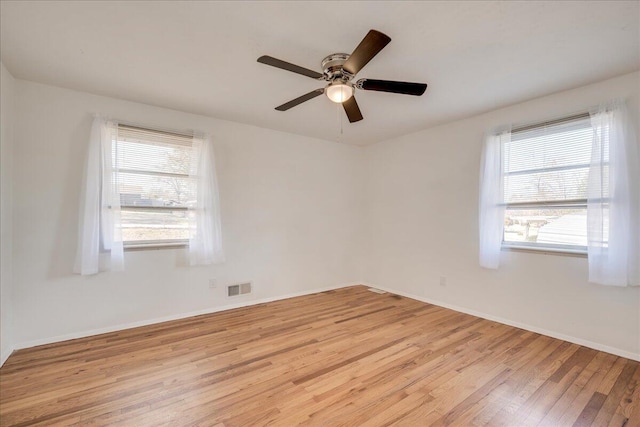 spare room with ceiling fan, a wealth of natural light, and light hardwood / wood-style flooring