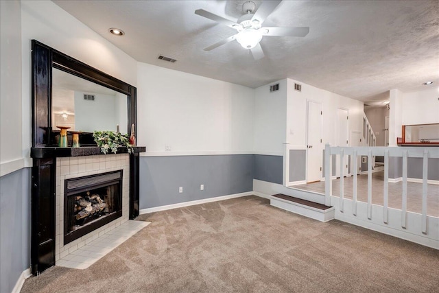 carpeted living room with visible vents, a fireplace, and a ceiling fan