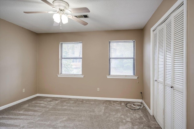 unfurnished bedroom featuring visible vents, a textured ceiling, a closet, carpet floors, and baseboards