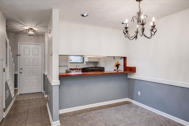 kitchen featuring a sink, baseboards, a chandelier, and freestanding refrigerator