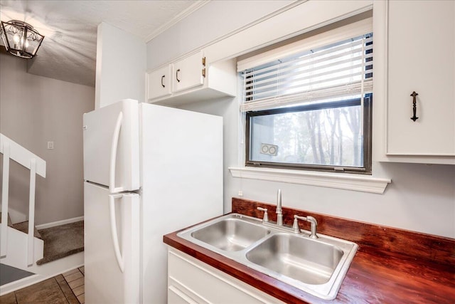 kitchen with tile patterned floors, a sink, dark countertops, white cabinetry, and freestanding refrigerator