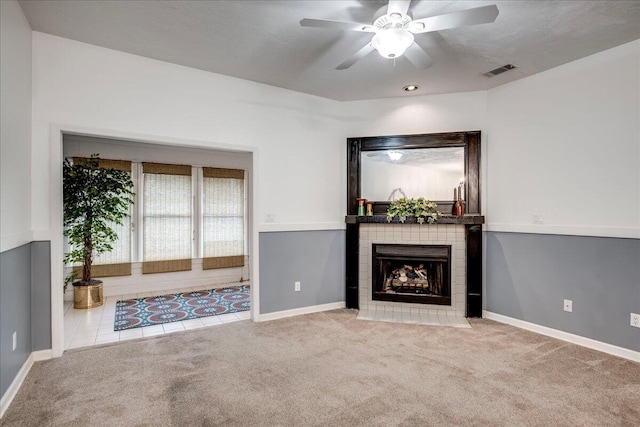 unfurnished living room featuring visible vents, carpet, a ceiling fan, and a tiled fireplace