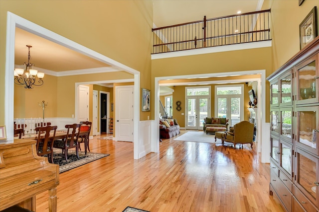 3005 Timber Woods Dr, Appling, GA 30802 - living room with french doors, a towering ceiling, light wood-type flooring, wainscoting, and a chandelier