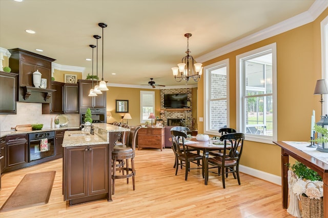 3005 Timber Woods Dr, Appling, GA 30802 - kitchen featuring black oven, a ceiling fan, a fireplace, dark brown cabinetry, and crown molding