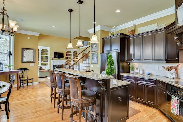 3005 Timber Woods Dr, Appling, GA 30802 - kitchen with black appliances, ornamental molding, a fireplace, light wood finished floors, and a kitchen bar