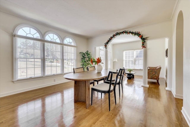 dining space with ornamental molding and light hardwood / wood-style floors