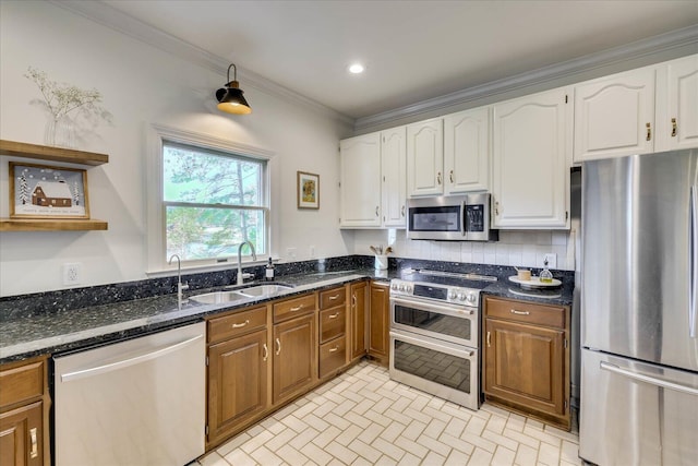 kitchen featuring white cabinetry, stainless steel appliances, sink, dark stone countertops, and crown molding