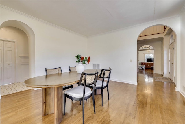 dining area with ornamental molding and light hardwood / wood-style floors