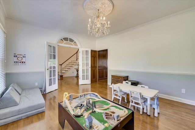 game room with ornamental molding, french doors, an inviting chandelier, and wood-type flooring