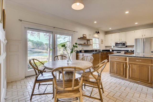 dining space with a water view, ornamental molding, and sink