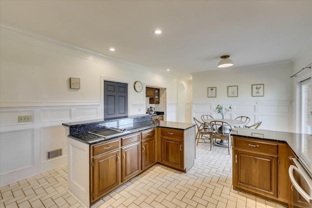 kitchen with dark stone countertops, crown molding, and a center island