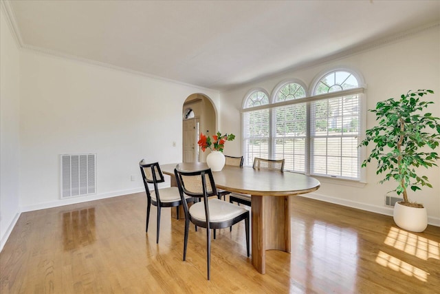 dining area with crown molding and light hardwood / wood-style floors