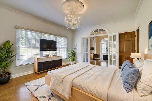 bedroom featuring a chandelier, crown molding, french doors, and hardwood / wood-style floors