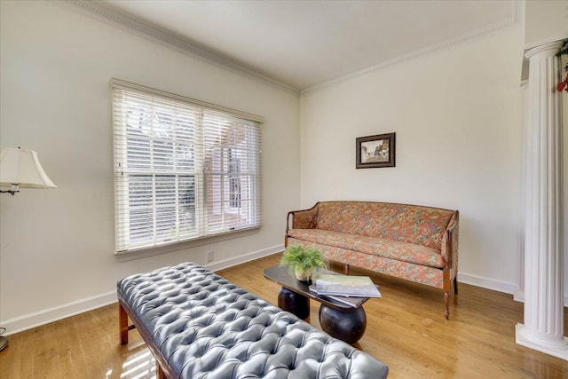 sitting room with hardwood / wood-style flooring, ornate columns, and ornamental molding