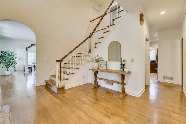 entryway with light wood-type flooring, a high ceiling, and crown molding