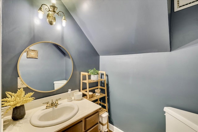 bathroom featuring vanity, toilet, and lofted ceiling