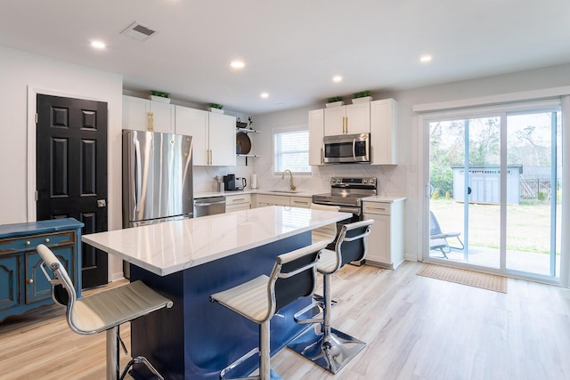 3609 Cameron Dr, Augusta, GA 30906 - kitchen with visible vents, a kitchen island, a kitchen bar, light wood-style flooring, and appliances with stainless steel finishes