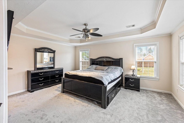 bedroom with light carpet, ceiling fan, a tray ceiling, and ornamental molding