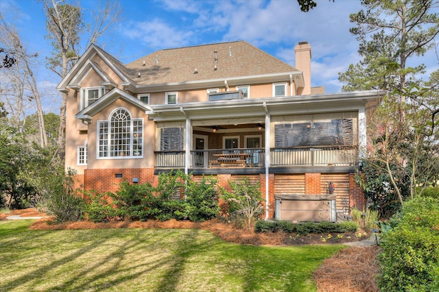 back of property featuring a ceiling fan, brick siding, a lawn, and a chimney