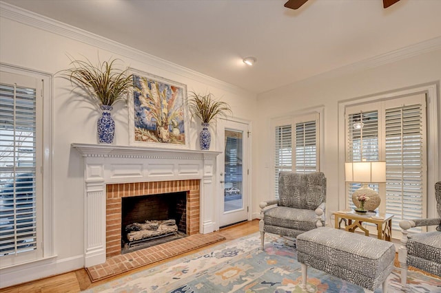 living area with a brick fireplace, light wood-style flooring, and crown molding