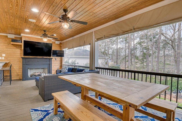 deck featuring outdoor dining area, ceiling fan, and an outdoor living space with a fireplace