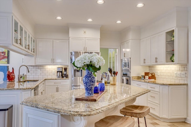 kitchen featuring light stone counters, stainless steel appliances, a sink, a kitchen island, and a kitchen bar