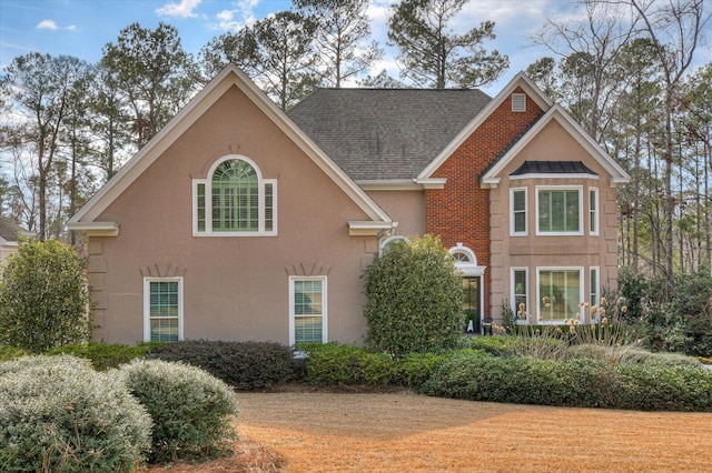 view of front facade featuring roof with shingles and stucco siding