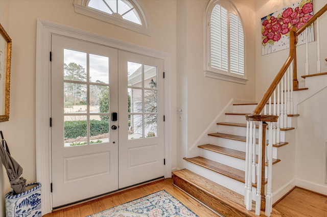 entryway with french doors, a healthy amount of sunlight, stairway, and light wood finished floors